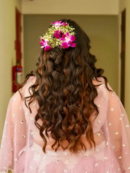 Another view of the Haldi hairstyle, showing a beautiful floral crown made of fresh orchids and baby's breath. This is a popular choice for pre-wedding events.