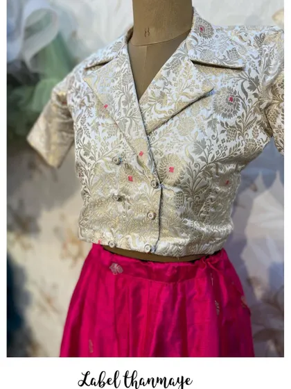 A unique Indo-Western set with a pink silk skirt and a white brocade blazer-style crop top.