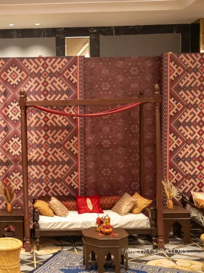 A cozy seating area with a touch of tradition. The wooden daybed is set against a backdrop of patola-print fabric, creating a comfortable and stylish nook for guests.
