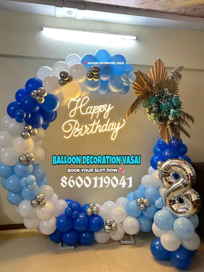 An 8th birthday celebration with a blue, white, and silver ring decoration. The setup is accented with a floral piece and a foil number balloon.