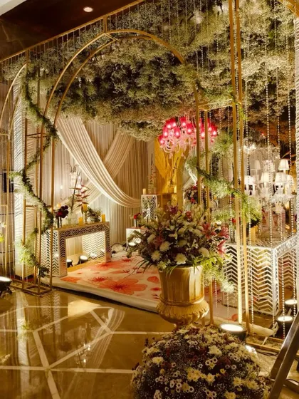A grand entrance with golden arches intertwined with lush greenery and baby's breath, creating a sophisticated and welcoming gateway to the celebration.