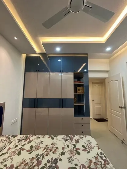 A full view of the oriental blue and mist grey wardrobe, showing how the color blocking creates a modern and visually interesting design. The ceiling with cove lighting adds to the room's sophisticated ambiance.