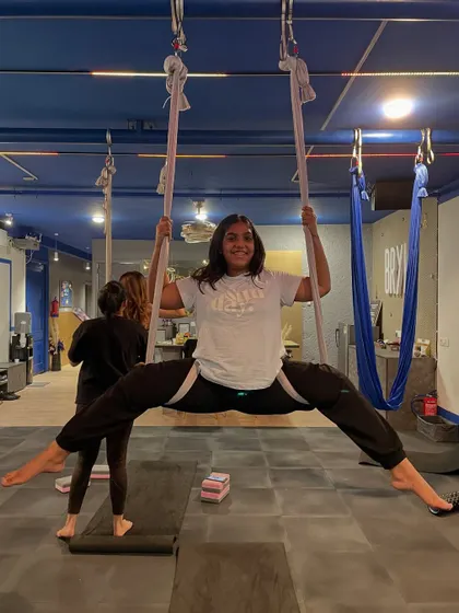 Achieving a full split in the hammock with a huge smile. This is a perfect example of celebrating a personal win within our supportive group.