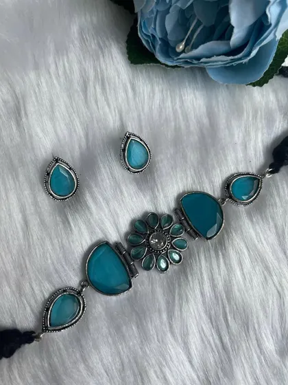 A flat-lay of the sold-out blue stone choker set, showing the delicate craftsmanship of the black polish silver replica and the matching teardrop earrings.