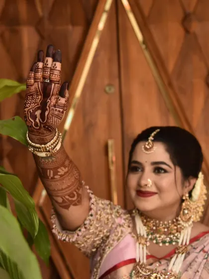 A happy client waving and showing off the detailed portrait work on her palm. The rich stain and intricate design are on full display, adding to her festive baby shower look.