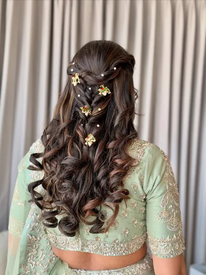 An elegant braided hairstyle with soft curls, adorned with delicate gold and pearl accessories.