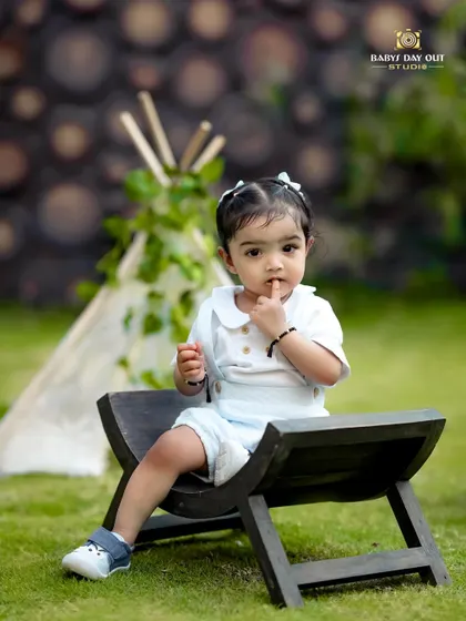 Cuteness overload! A little one gives a shy look while sitting in front of a lace teepee in our garden.