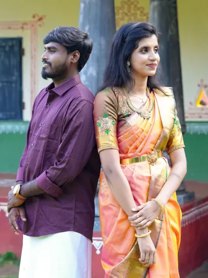A sweet back-to-back pose that captures the couple's connection, set against a colorful, traditional Indian house.