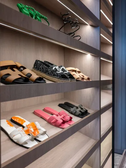 A close-up of the shoe display shelves in a custom wardrobe. The soft, integrated lighting and angled shelves turn a practical storage solution into an elegant showcase for a prized collection.