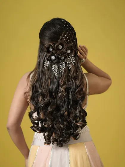 The model's pose highlights the beautiful details of this intricate half-up style. The combination of textures and sparkle is truly stunning.