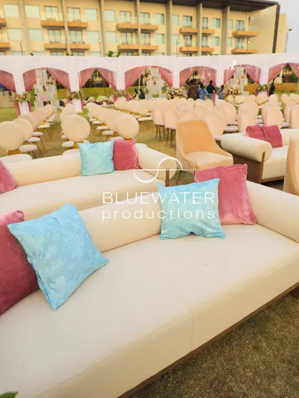 Comfortable lounge seating on the lawn for an outdoor wedding, with pastel cushions adding a touch of color to the neutral sofas.