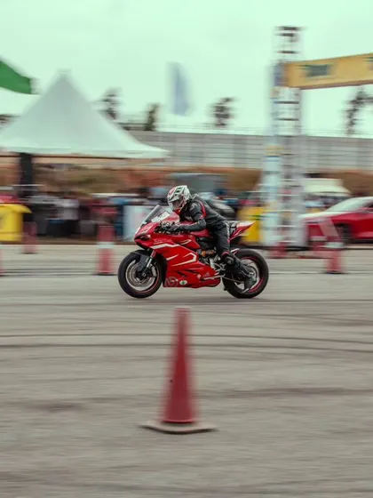 A distant shot of the red Ducati, showing its position on the track as it speeds towards the finish line. The entire venue is designed for optimal racing and viewing.