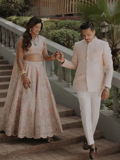 A candid shot of the couple descending a grand staircase, showcasing the flow and detail of the bride's beautiful lehenga.
