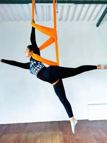 A student demonstrates a beautiful arabesque in the aerial hammock, showcasing the elegance and control developed in aerial practice.