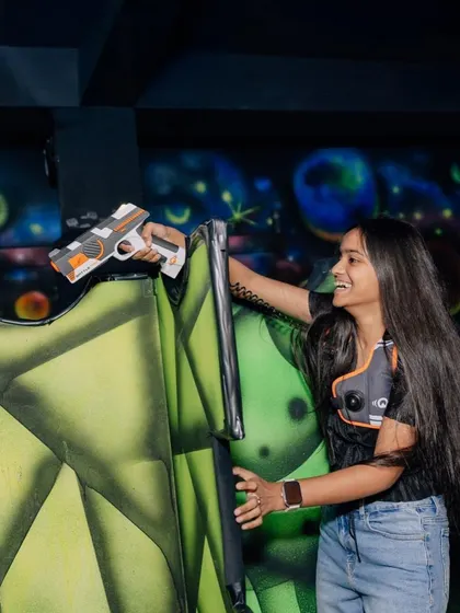A player takes aim from behind cover, showcasing the strategic gameplay and fun atmosphere of our laser tag arena.