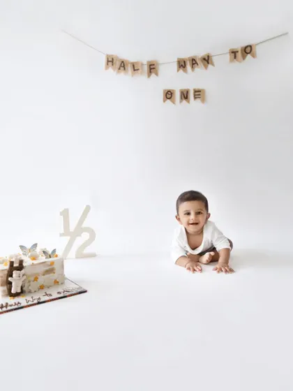 A classic tummy-time pose for a six-month-old. The simple white background and banner keep this shot feeling timeless.