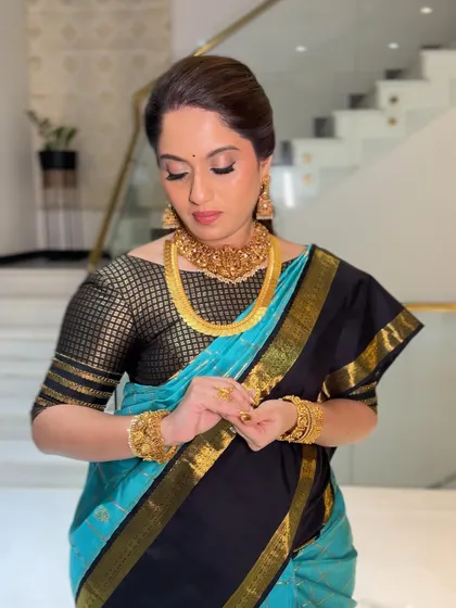 A candid moment of the client adjusting her jewelry. The saree drape remains impeccable, highlighting the importance of a secure and professional draping service.