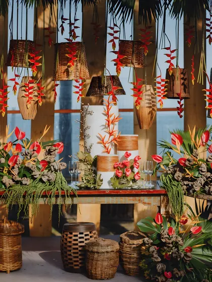 This tropical-themed engagement celebration was a feast for the senses. The cake table combines rustic wood and wicker textures with vibrant heliconia and anthurium flowers, perfectly capturing a spirit of wild elegance and romantic celebration.