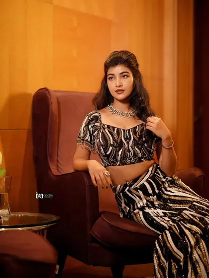 This seated portrait has a modern, editorial feel. The bold black and white pattern of the lehenga is striking, and the pose is confident and relaxed.