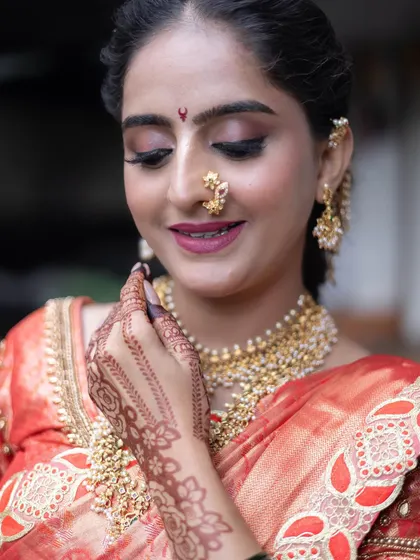 A detailed shot of the bride's makeup, nath, and jewellery, all perfectly complementing the rich orange silk of the Nauvari.