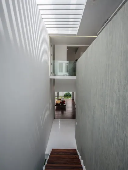 skylight… casting linear shadows along a corridor, turning a simple passage into a play of light and texture.