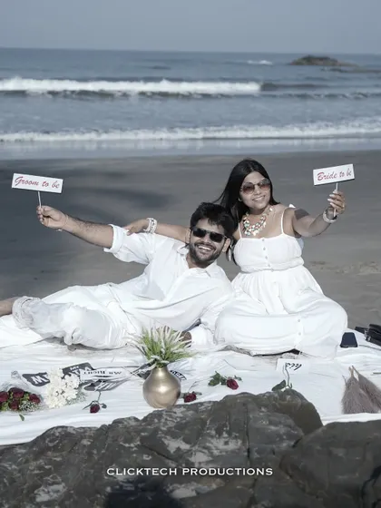 A fun picnic setup on a Goan beach, with the couple holding 'Groom to be' and 'Bride to be' signs.