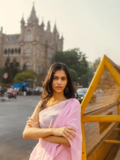 A powerful stance in front of the iconic Chhatrapati Shivaji Maharaj Terminus. The yellow barricade adds a pop of color and a gritty, urban feel.