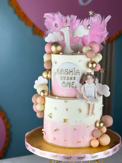 Turning one never looked so sweet. This angelic first birthday cake features soft pink and white ombre, fluffy clouds, and a sparkling number one topper for a heavenly celebration.