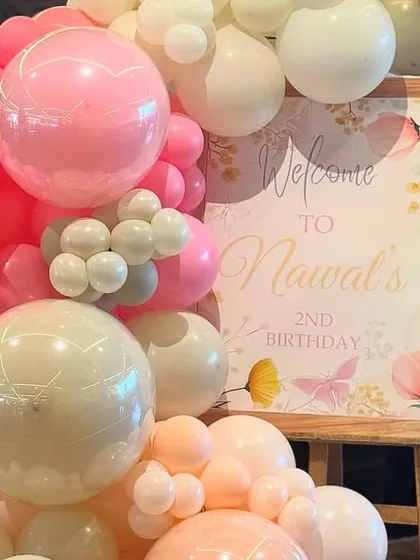 A beautiful welcome sign for a second birthday, nestled in a stunning organic balloon garland of pink, peach, and white. Butterfly details add a touch of whimsy.