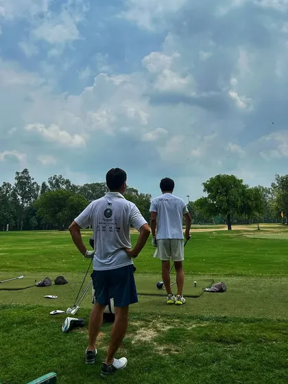 Two golfers take a moment to watch the shots fly. The range is a great place to learn from and connect with fellow players.