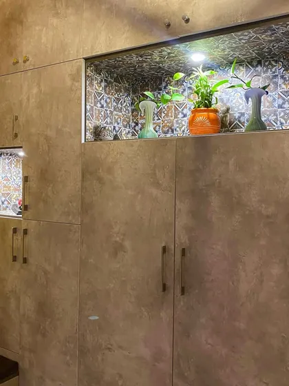 A storage unit with a textured finish and an illuminated niche for plants and decor, adding a unique touch to the room.