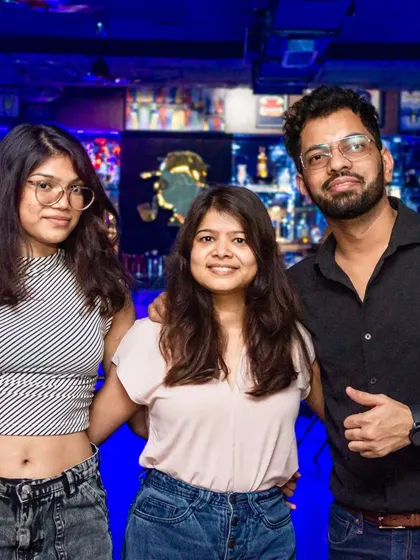 Three friends enjoying the party. The blue lighting and bar in the background show off the modern, energetic side of the pub.