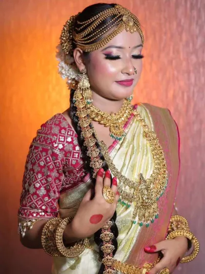 A model showcasing a unique South Indian bridal look with a side-swept hair braid adorned with heavy gold-plated jewellery.