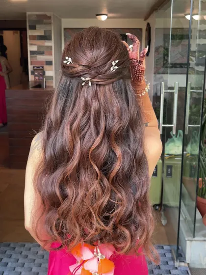 A half up, half down hairstyle perfect for a Mehndi ceremony. The hair is twisted back and adorned with small, delicate leaf pins.