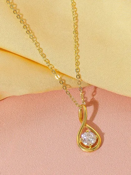This infinity loop diamond pendant is shot against a two tone pink and yellow background. The clean composition and soft colors make it look like a modern and graceful piece.