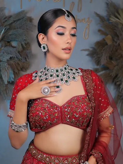 The complete royal look. The intricate red lehenga, heavy jewelry, and elegant makeup come together to create a breathtaking bridal vision.
