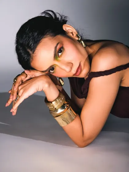 An intimate, floor-posed shot that combines vulnerability with strength. The rich colors and heavy accessories add to the narrative of the series.