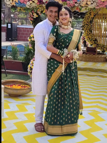 A happy couple at their Haldi ceremony, with the bride wearing a green saree I draped into a lehenga. This style is both traditional in fabric and modern in form.