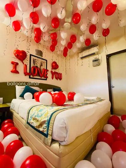 A close-up on the bed, showing the mix of red and white balloons and the clear "I LOVE YOU" banner, perfect for a romantic gesture.
