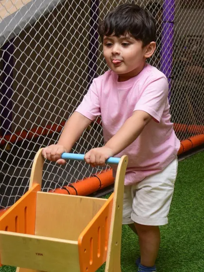 This little shopper is on the move, pushing his wooden cart through the play zone.
