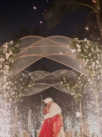 A dramatic shot of the couple's embrace under the modern mandap, illuminated by a burst of cold pyro fireworks. This is how I create unforgettable moments.