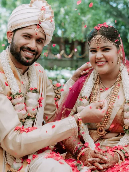 A happy, candid portrait of the couple during their wedding ceremony, showered with petals.