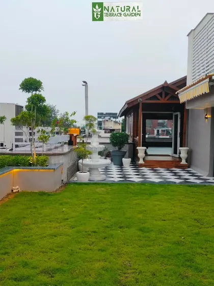 Another angle of the New Friends Colony project, showing the connection between the lawn, the patio, and the wooden cottage.
