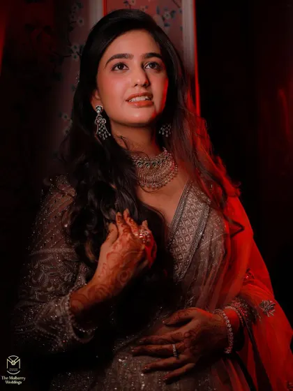 A dramatic and artistic shot from an engagement ceremony. The lighting highlights the flawless makeup and the client's radiant expression.