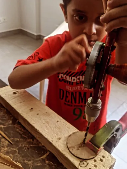 Using a clamp to secure the wood, this student drills a hole for their project. We emphasize proper setup and safety in all our woodworking activities.