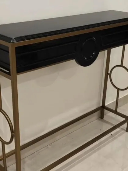 A black and gold console table with geometric side details. This piece combines classic art deco elements with a modern finish for a truly elegant look.