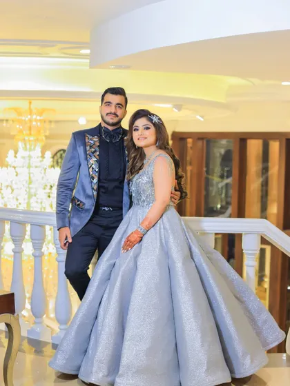 A classic couple portrait on a grand staircase. The bride's silver ball gown and the groom's stylish blue tuxedo create a look of modern royalty.