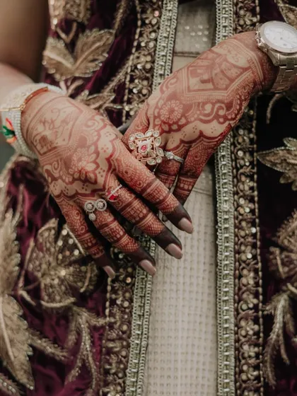 A close-up shot of the bride's hands, showcasing her intricate henna design and beautiful rings. We believe in capturing the details that tell a deeper story.