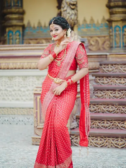 A standing pose that highlights the elegance and grace of the traditional red saree ensemble we provided.