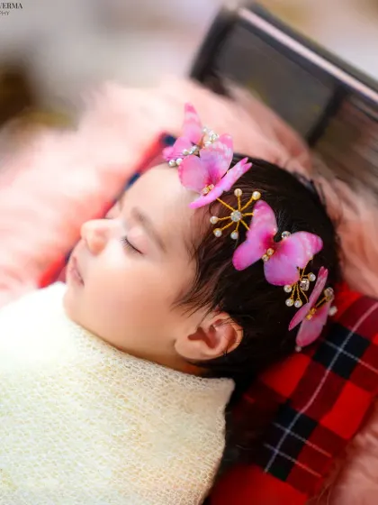 A side profile of a sleeping newborn, highlighting the delicate features and the beautiful butterfly headband. These detailed shots are precious keepsakes.